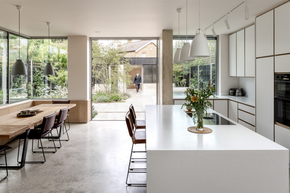 Inspiration for a modern l-shaped eat-in kitchen in Surrey with flat-panel cabinets, white cabinets, solid surface benchtops, white splashback, concrete floors, with island, grey floor and yellow benchtop.