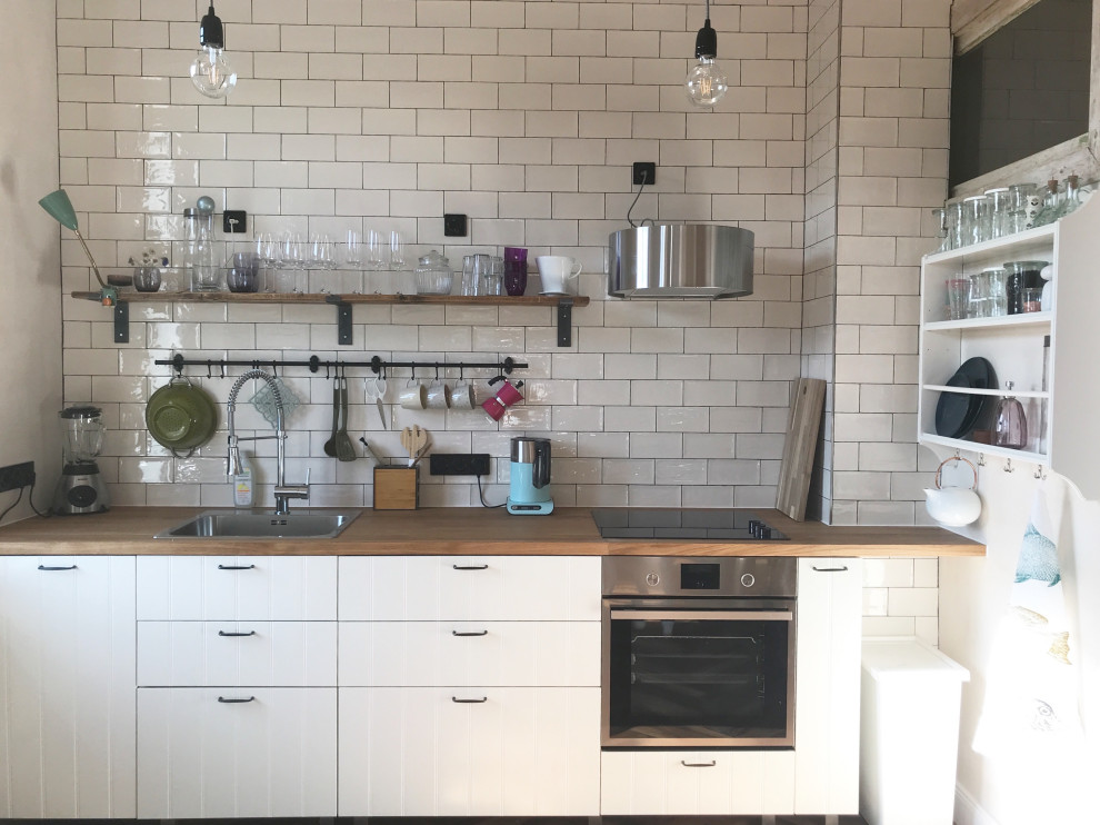 Design ideas for a large country single-wall open plan kitchen in Berlin with beaded inset cabinets, white cabinets, wood benchtops, white splashback, subway tile splashback, painted wood floors, no island and brown benchtop.
