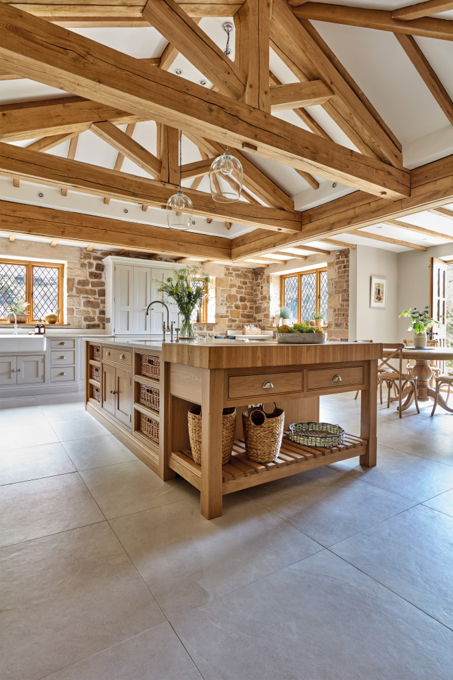 Inspiration for a large country u-shaped eat-in kitchen in West Midlands with a farmhouse sink, shaker cabinets, beige cabinets, quartzite benchtops, white splashback, engineered quartz splashback, stainless steel appliances, with island, beige floor and white benchtop.