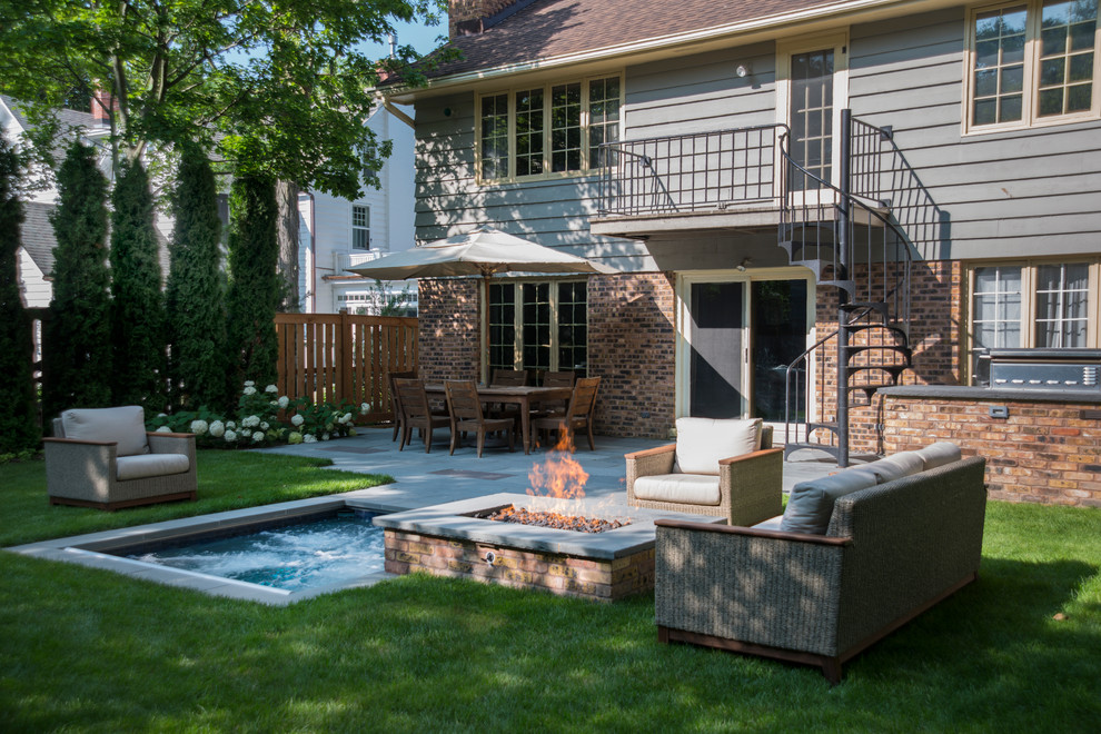 This is an example of a small traditional backyard rectangular pool in Chicago with a hot tub and natural stone pavers.
