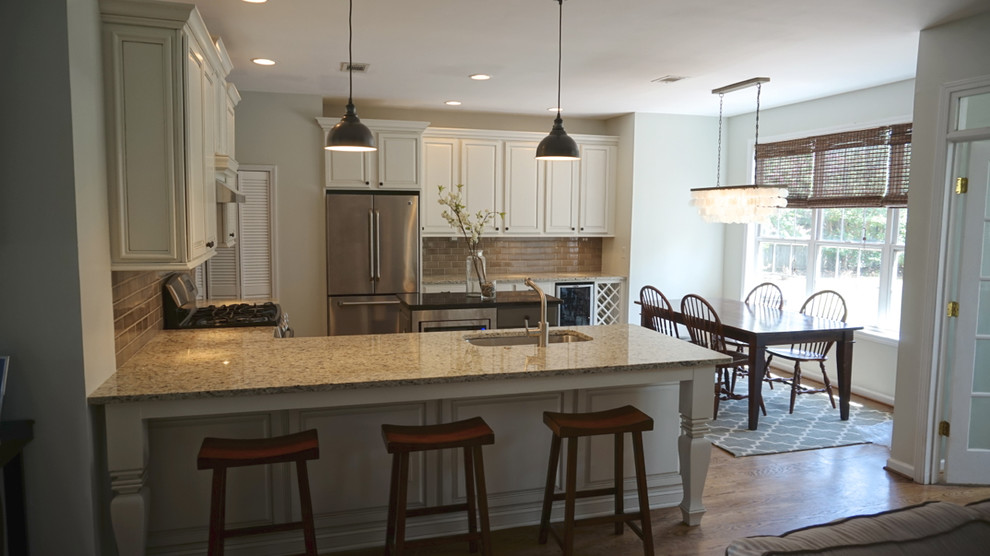 Large transitional u-shaped medium tone wood floor eat-in kitchen photo in Atlanta with an undermount sink, raised-panel cabinets, white cabinets, granite countertops, gray backsplash, ceramic backsplash, stainless steel appliances and an island