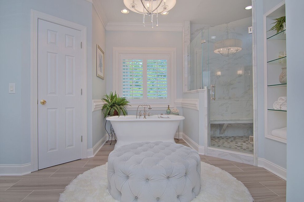 Design ideas for a large transitional master bathroom in Charlotte with a freestanding tub, an alcove shower, gray tile, marble, blue walls, vinyl floors, marble benchtops, brown floor, a hinged shower door, shaker cabinets, white cabinets, a two-piece toilet and an undermount sink.