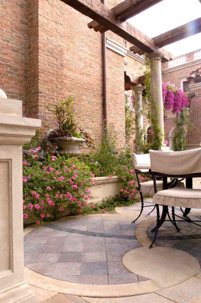 Design ideas for an expansive traditional courtyard patio in Chicago with natural stone pavers and no cover.