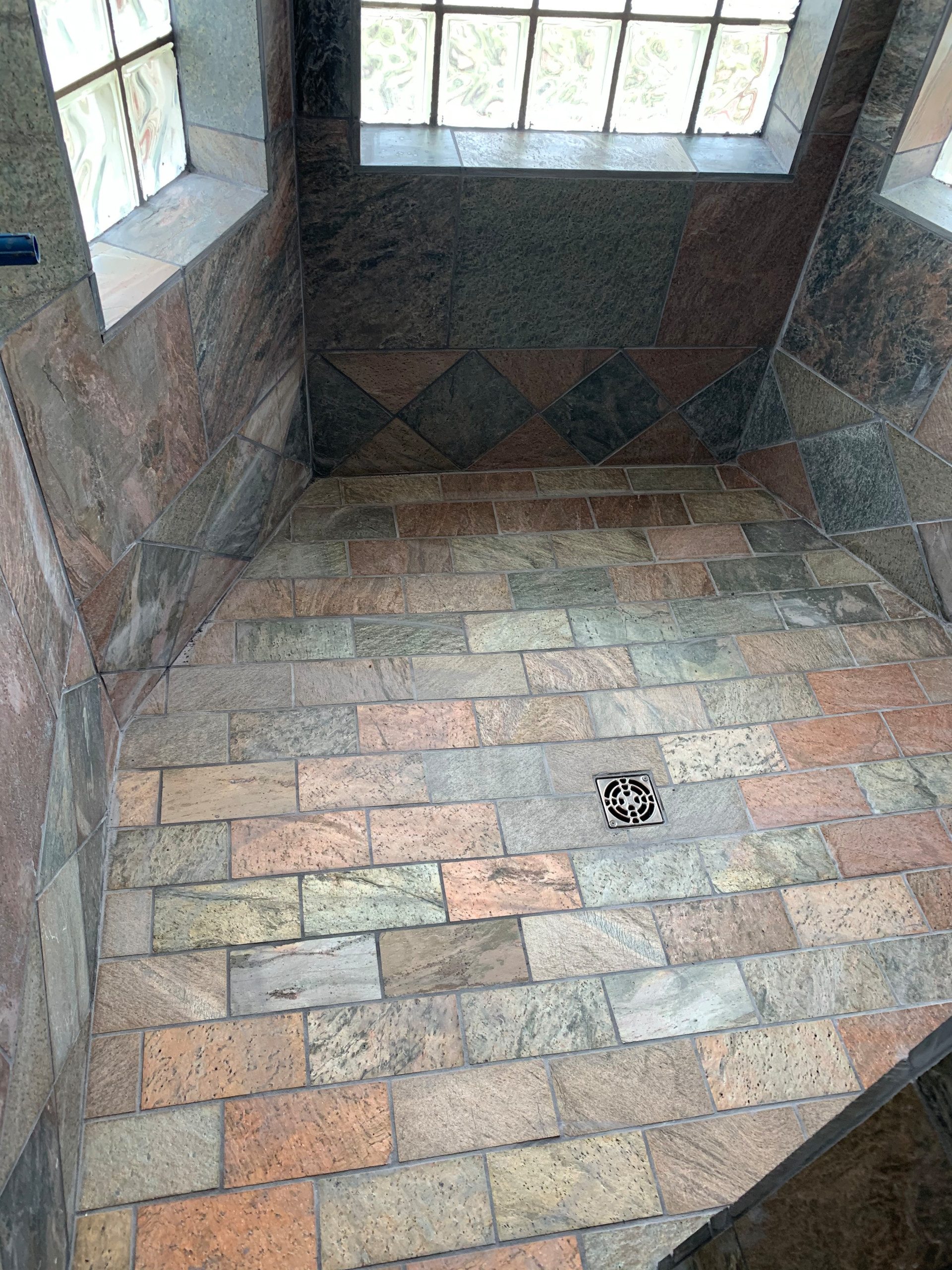 Stone tile walk in shower with rain head and body misters.