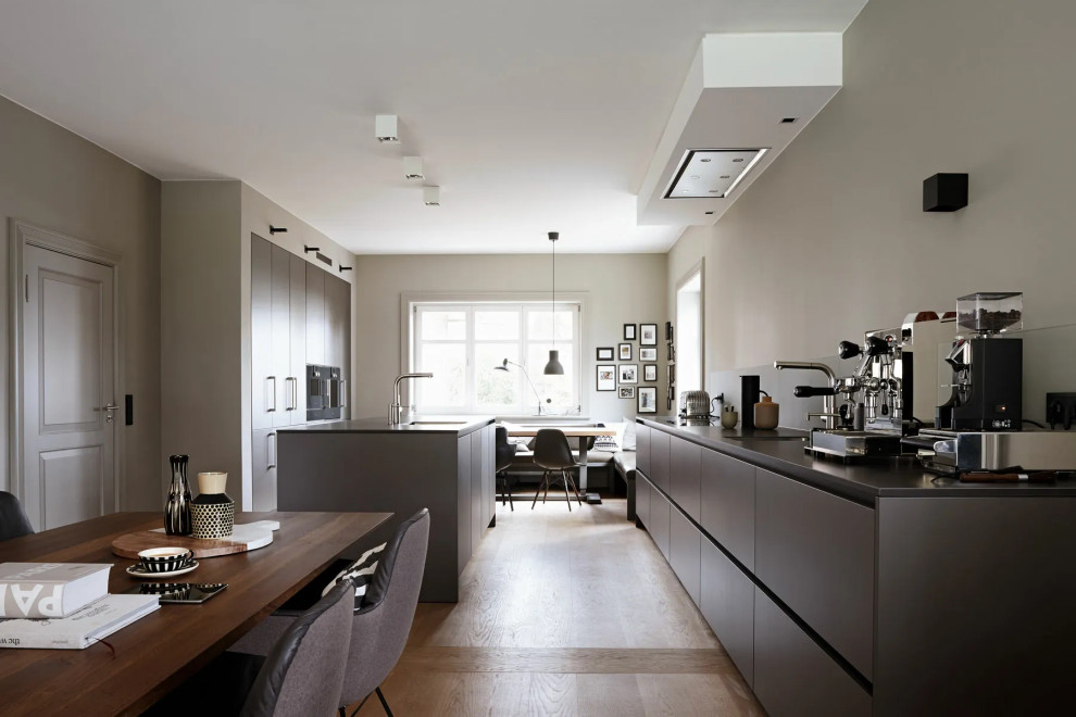 Foto de cocina comedor actual de tamaño medio con armarios con paneles lisos, electrodomésticos negros y una isla