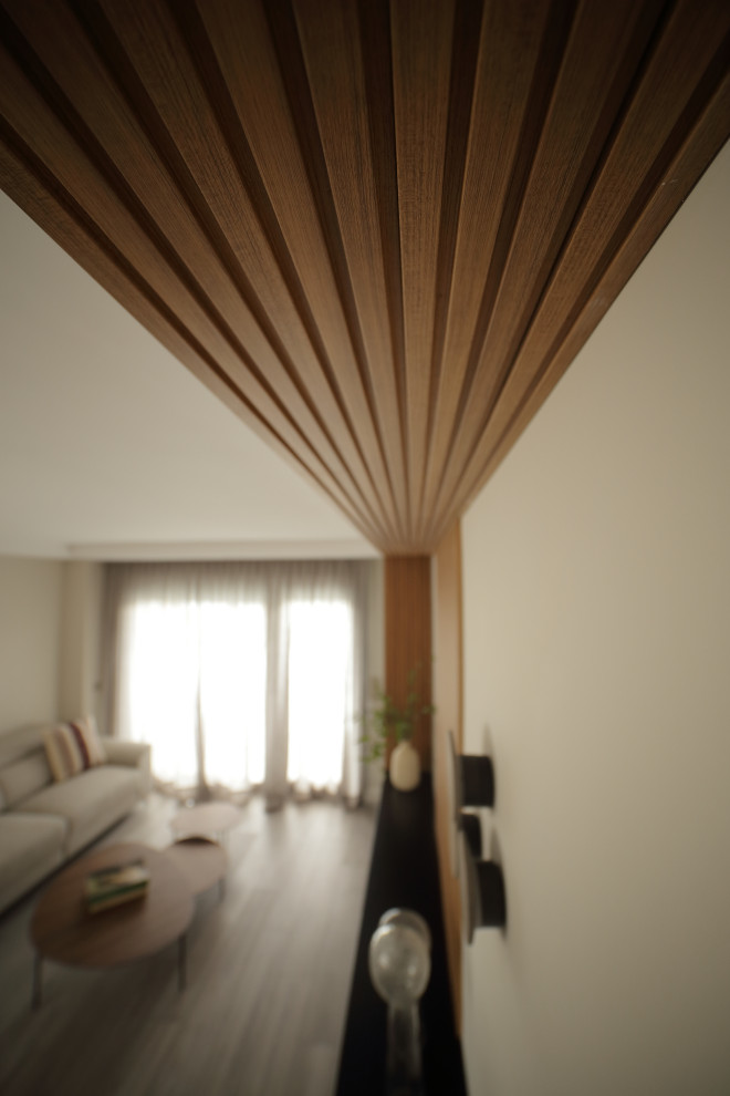 Ejemplo de salón cerrado y gris y negro moderno de tamaño medio con paredes beige, suelo de madera clara, pared multimedia, suelo gris y papel pintado