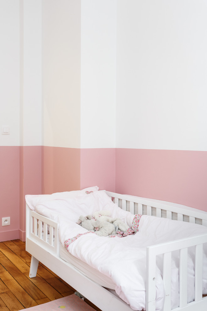 Inspiration for a mid-sized scandinavian gender-neutral kids' bedroom for kids 4-10 years old in Other with pink walls, medium hardwood floors and brown floor.