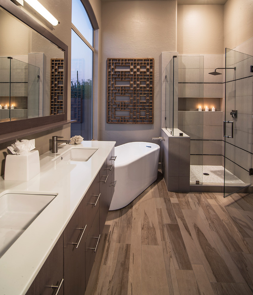 Photo of a large contemporary master bathroom in Phoenix with a freestanding tub, flat-panel cabinets, brown cabinets, a corner shower, beige tile, porcelain tile, beige walls, dark hardwood floors, an undermount sink, quartzite benchtops, brown floor, a hinged shower door and white benchtops.