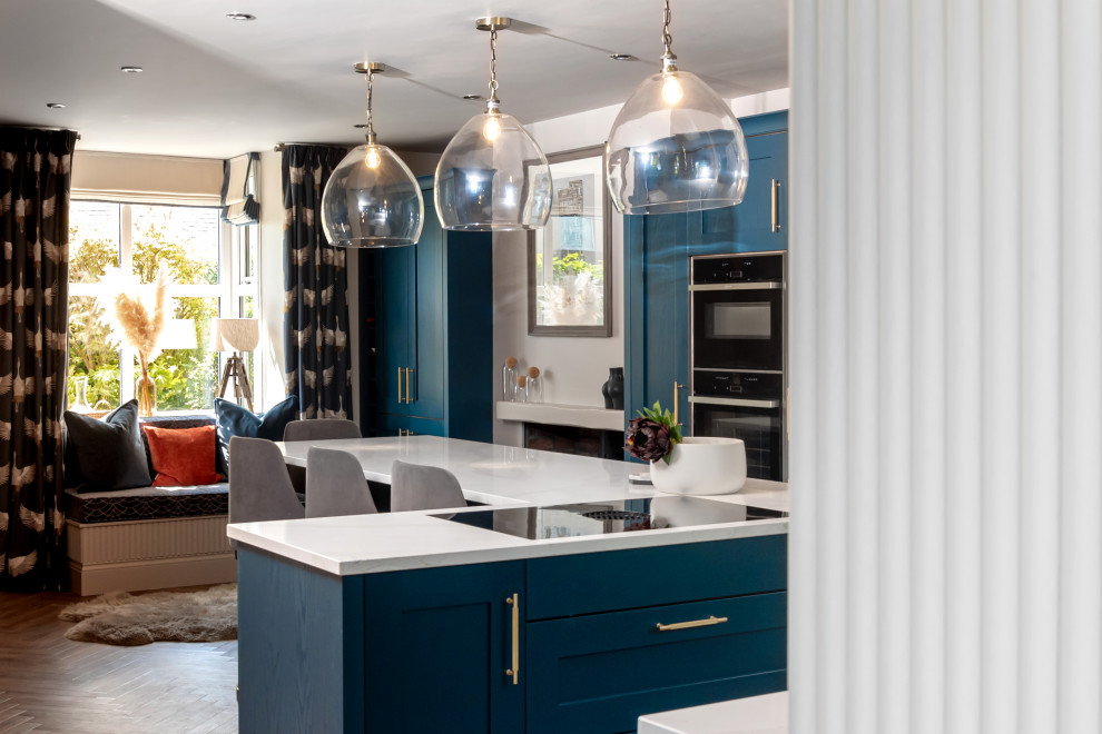 На фото: угловая кухня среднего размера в современном стиле с фасадами в стиле шейкер, синими фасадами, гранитной столешницей, белым фартуком, островом и белой столешницей