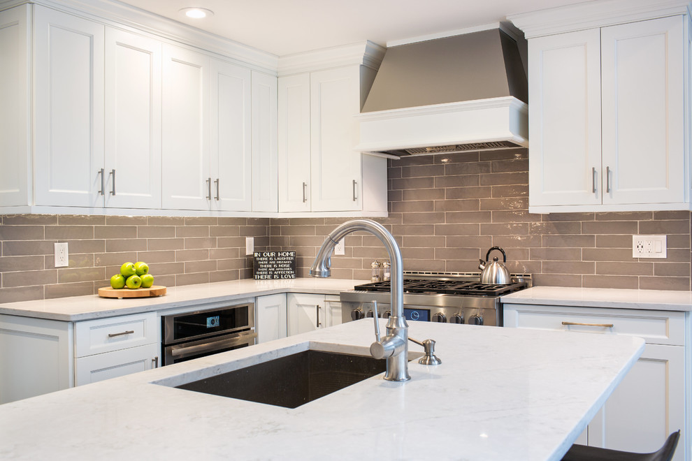 Example of a large transitional ceramic tile open concept kitchen design in New York with an undermount sink, shaker cabinets, white cabinets, quartz countertops, gray backsplash, ceramic backsplash, stainless steel appliances and an island