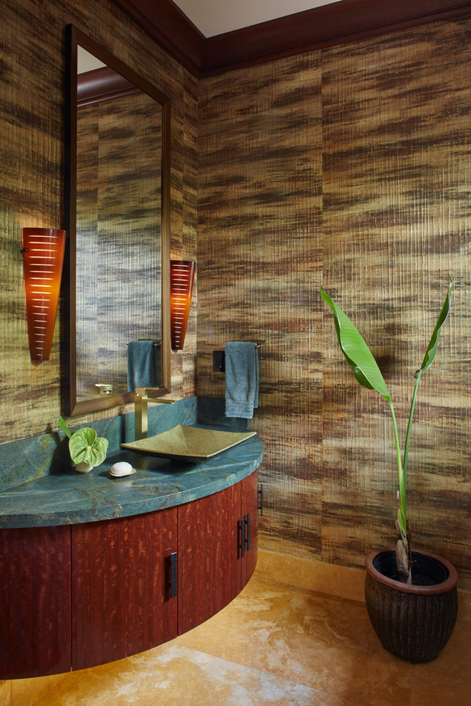 This is an example of a large tropical powder room in Hawaii with a vessel sink, furniture-like cabinets, dark wood cabinets, granite benchtops, a one-piece toilet, multi-coloured walls, travertine floors and blue benchtops.