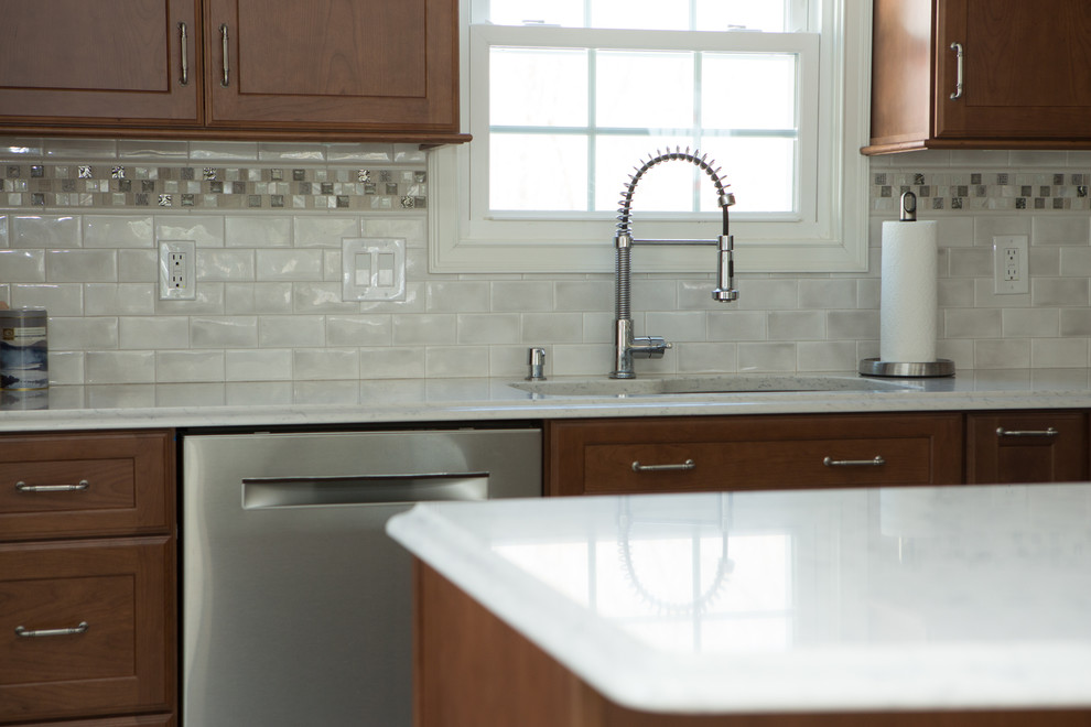 Example of a mid-sized transitional l-shaped white floor and ceramic tile eat-in kitchen design with an undermount sink, shaker cabinets, medium tone wood cabinets, white backsplash, stainless steel appliances, a peninsula, white countertops, quartz countertops and porcelain backsplash