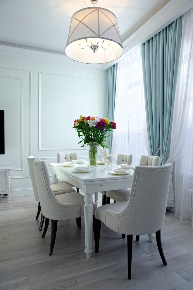 This is an example of a transitional dining room in Moscow with white walls and light hardwood floors.