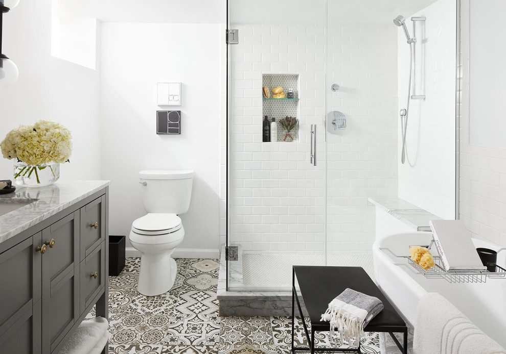 Inspiration for a mid-sized transitional bathroom in Chicago with grey cabinets, a freestanding tub, a corner shower, a two-piece toilet, white tile, ceramic tile, white walls, porcelain floors, an undermount sink, grey floor, a hinged shower door, white benchtops and shaker cabinets.