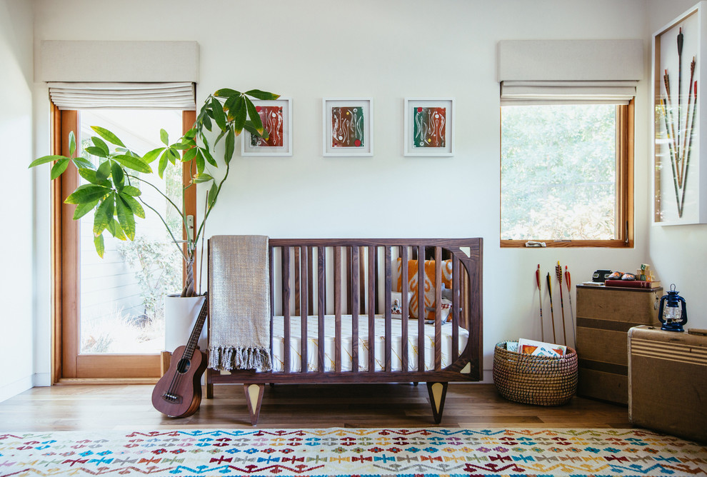 На фото: нейтральная комната для малыша среднего размера в стиле ретро с белыми стенами и паркетным полом среднего тона с