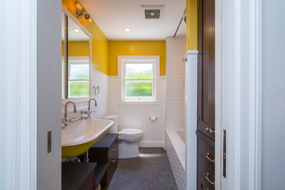 This is an example of a mid-sized transitional master bathroom in San Francisco with a floating vanity, flat-panel cabinets, dark wood cabinets, a drop-in tub, white tile, yellow walls, mosaic tile floors, a wall-mount sink, grey floor, a single vanity and decorative wall panelling.