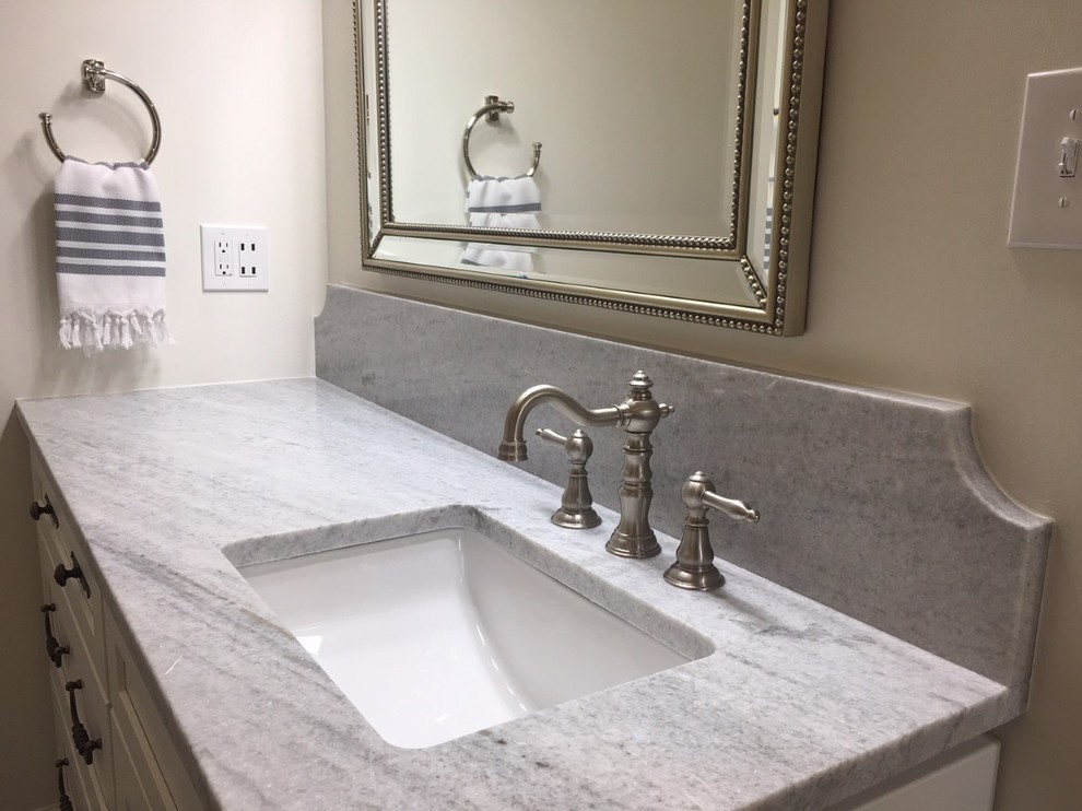 Mid-sized transitional master white tile and ceramic tile porcelain tile and gray floor corner shower photo with recessed-panel cabinets, white cabinets, an undermount tub, a two-piece toilet, gray walls, an undermount sink, marble countertops and a hinged shower door