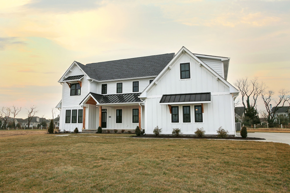 Idées déco pour une grande façade de maison blanche campagne en panneau de béton fibré et planches et couvre-joints à un étage avec un toit à deux pans et un toit noir.