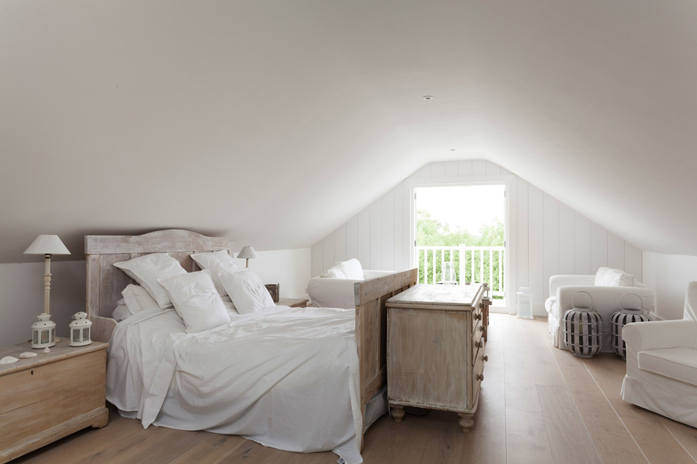 Photo of a beach style master bedroom in London with white walls and light hardwood floors.
