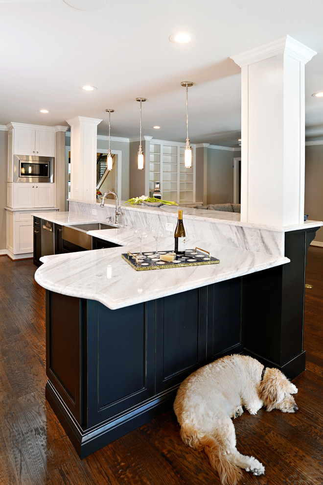 Inspiration for a large transitional single-wall dark wood floor eat-in kitchen remodel in Dallas with a farmhouse sink, shaker cabinets, white cabinets, marble countertops, beige backsplash, glass tile backsplash, stainless steel appliances and an island