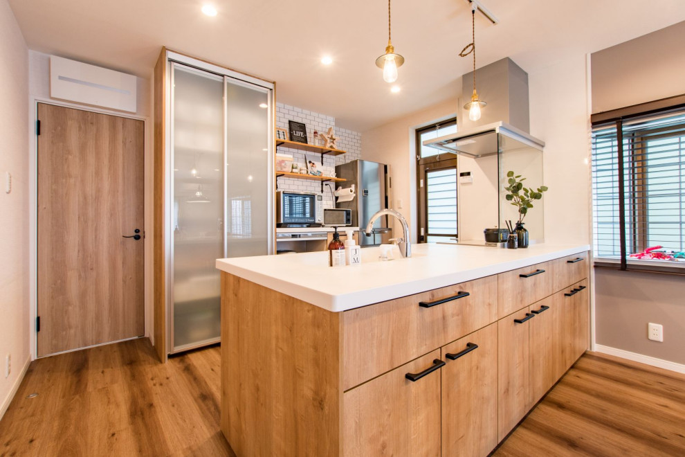 Design ideas for an industrial single-wall open plan kitchen in Other with an integrated sink, flat-panel cabinets, medium wood cabinets, solid surface benchtops, stainless steel appliances, medium hardwood floors, a peninsula, brown floor, white benchtop, wallpaper and glass sheet splashback.
