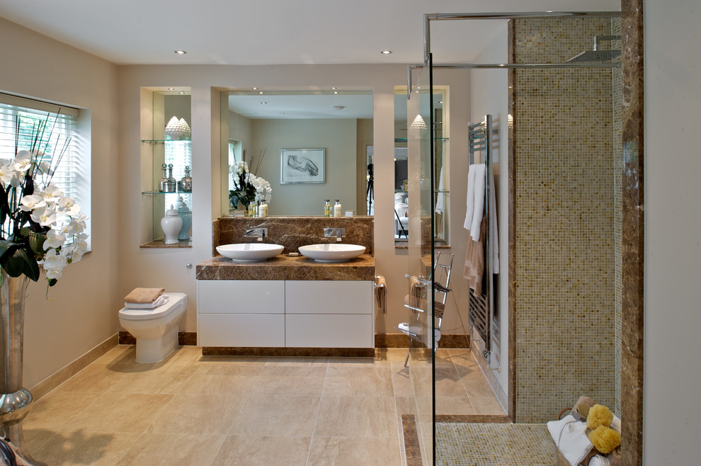Inspiration for a transitional master bathroom in London with a vessel sink, flat-panel cabinets, white cabinets, a curbless shower, a one-piece toilet, beige tile, mosaic tile, limestone benchtops and brown benchtops.