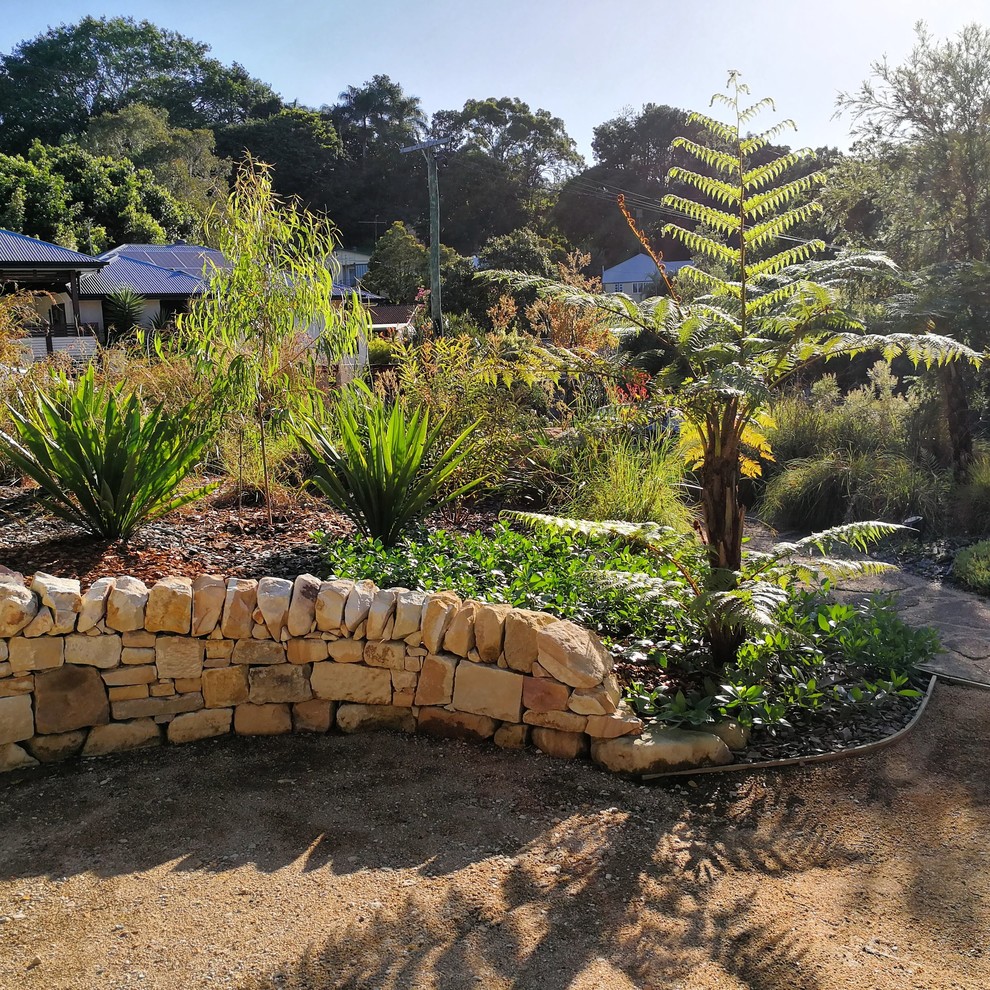 Photo of a mid-sized and australian native country front yard full sun xeriscape in Sunshine Coast with a retaining wall and gravel.