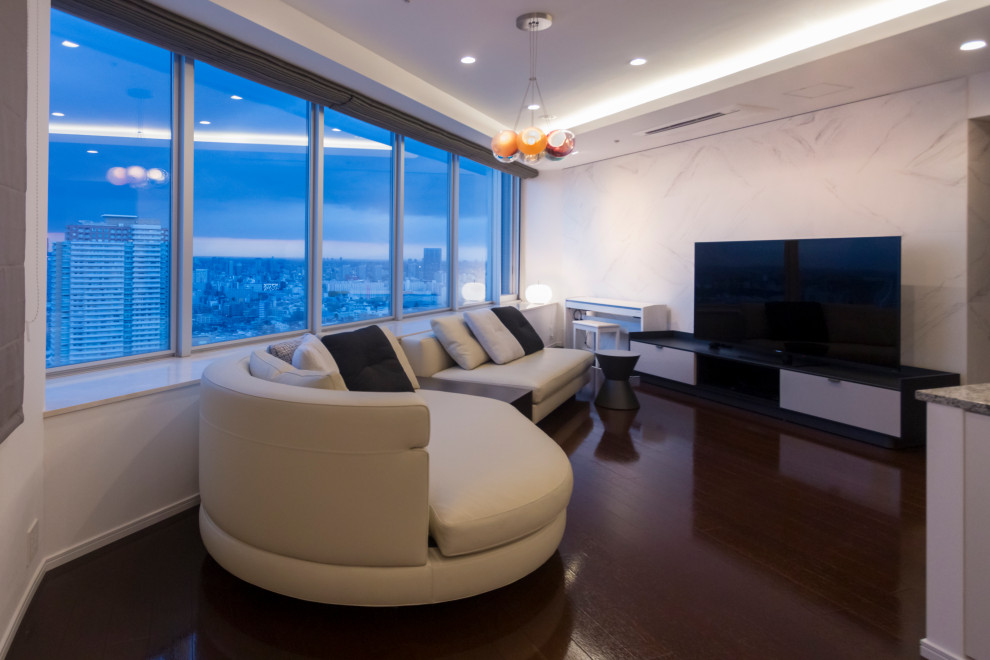 Exempel på ett modernt allrum med öppen planlösning, med vita väggar, en fristående TV och brunt golv