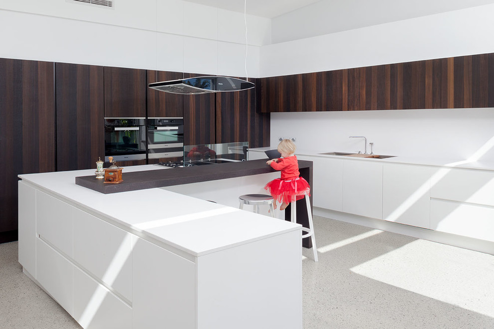 Photo of a large contemporary eat-in kitchen in Perth with quartz benchtops, white splashback, stainless steel appliances, concrete floors and with island.