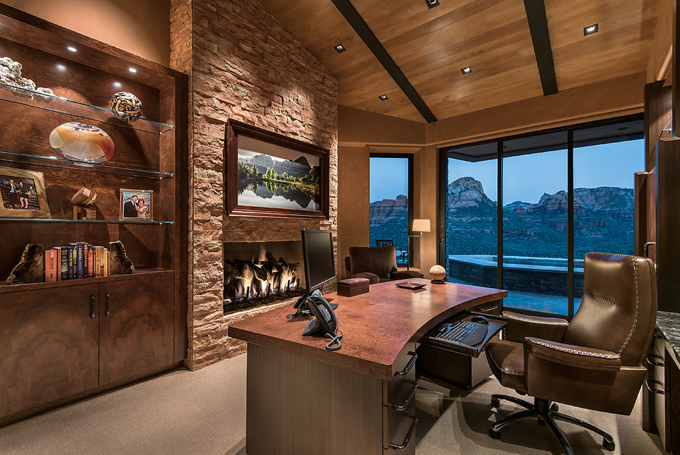 Design ideas for a mid-sized contemporary study room in Phoenix with carpet, a standard fireplace, a stone fireplace surround, a freestanding desk and brown walls.