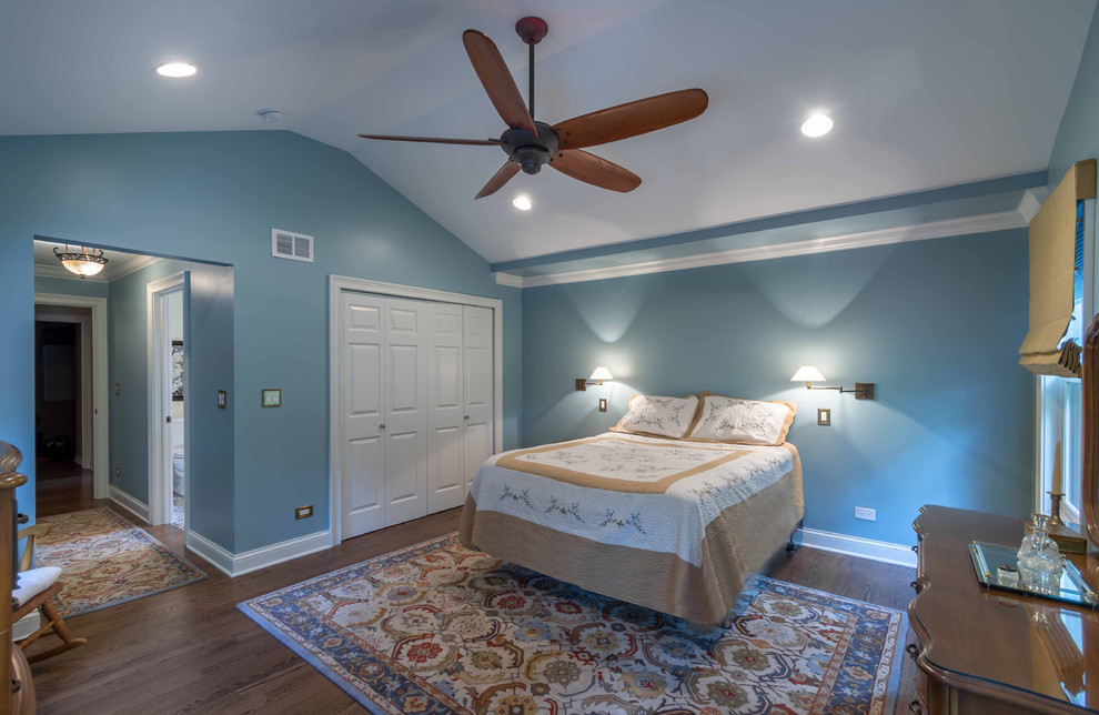 Photo of a mid-sized traditional master bedroom in Chicago with blue walls, medium hardwood floors, brown floor, no fireplace, vaulted and wallpaper.