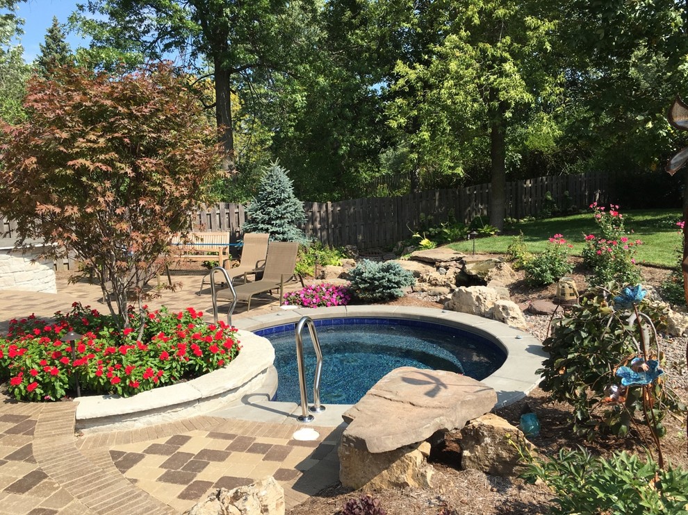Small traditional side yard round natural pool in Orlando with a water feature and brick pavers.