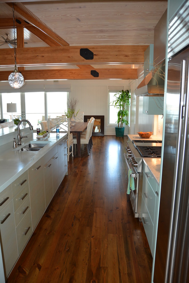 Enclosed kitchen - large l-shaped light wood floor enclosed kitchen idea in Orange County with an undermount sink, flat-panel cabinets, blue cabinets, solid surface countertops, white backsplash, porcelain backsplash, stainless steel appliances and an island