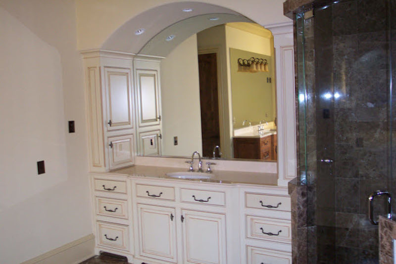 Inspiration for a mid-sized mediterranean master bathroom in Charlotte with raised-panel cabinets, white cabinets, a corner shower, brown tile, stone tile, white walls, dark hardwood floors, an undermount sink, engineered quartz benchtops, brown floor and a hinged shower door.