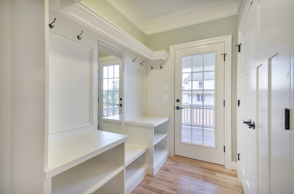 This is an example of a traditional mudroom in Other with green walls, light hardwood floors, a dutch front door, a white front door and brown floor.