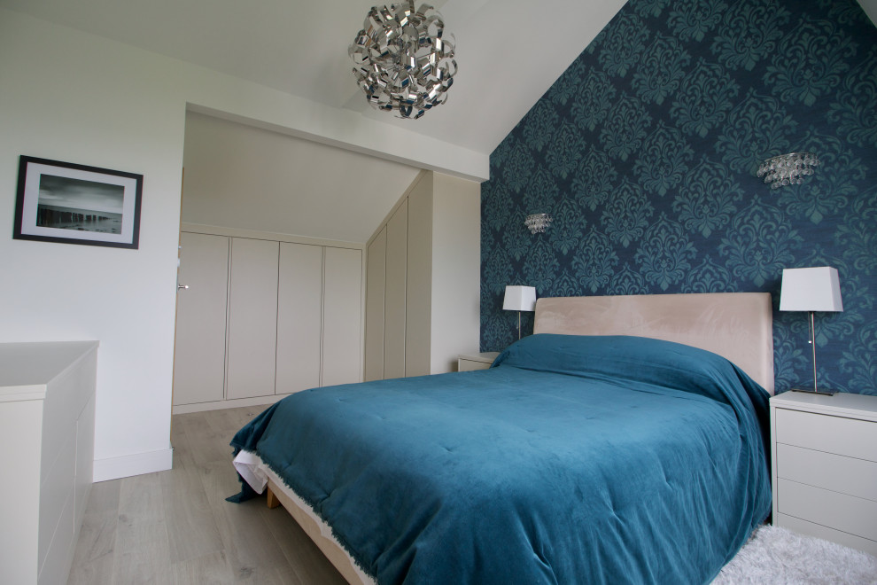 Mittelgroßes Modernes Hauptschlafzimmer mit blauer Wandfarbe, Laminat, beigem Boden, gewölbter Decke und Tapetenwänden in Hampshire
