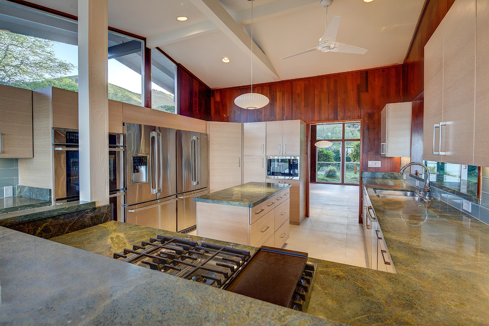 Mid-sized midcentury u-shaped kitchen in Hawaii with an undermount sink, flat-panel cabinets, light wood cabinets, granite benchtops, blue splashback, glass tile splashback, stainless steel appliances, porcelain floors and with island.