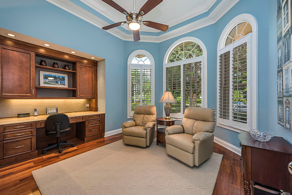 Large contemporary home office in Miami with blue walls, medium hardwood floors, a built-in desk and brown floor.