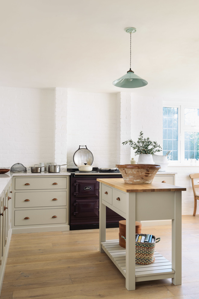 This is an example of a mid-sized country l-shaped open plan kitchen in Other with a farmhouse sink, shaker cabinets, beige cabinets, quartzite benchtops, white splashback, brick splashback, coloured appliances, medium hardwood floors and with island.