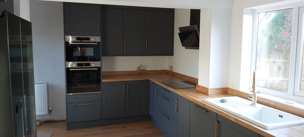 Design ideas for a medium sized contemporary l-shaped kitchen in Other with a built-in sink, shaker cabinets, green cabinets and wood worktops.