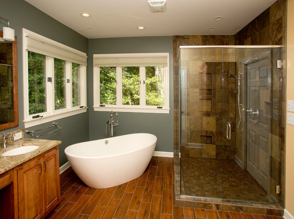 Inspiration for a mid-sized modern master bathroom in Other with an undermount sink, raised-panel cabinets, medium wood cabinets, granite benchtops, a freestanding tub, brown tile, grey walls, ceramic floors, a corner shower, ceramic tile, brown floor and a hinged shower door.