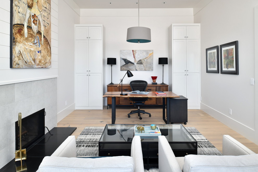 Photo of a beach style study room in Seattle with white walls, light hardwood floors, a ribbon fireplace, a tile fireplace surround and a freestanding desk.