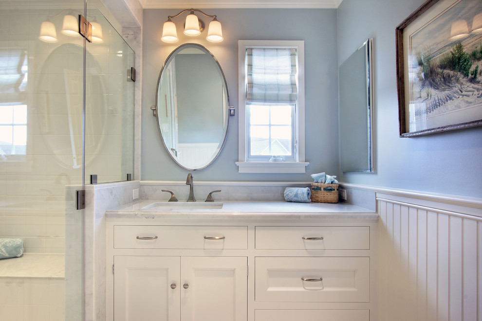 Inspiration for a mid-sized transitional bathroom in Philadelphia with a drop-in sink, recessed-panel cabinets, white cabinets, marble benchtops, an alcove shower, white tile, stone tile, blue walls and marble floors.