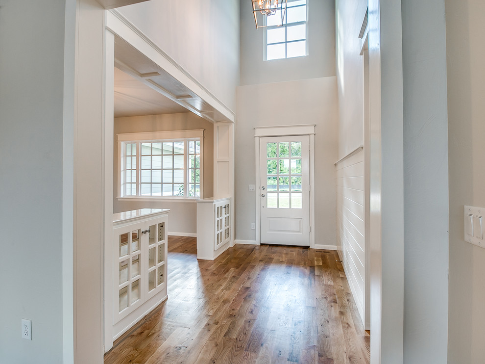 Photo of a large transitional front door in Oklahoma City with grey walls, light hardwood floors, a single front door, a white front door and brown floor.