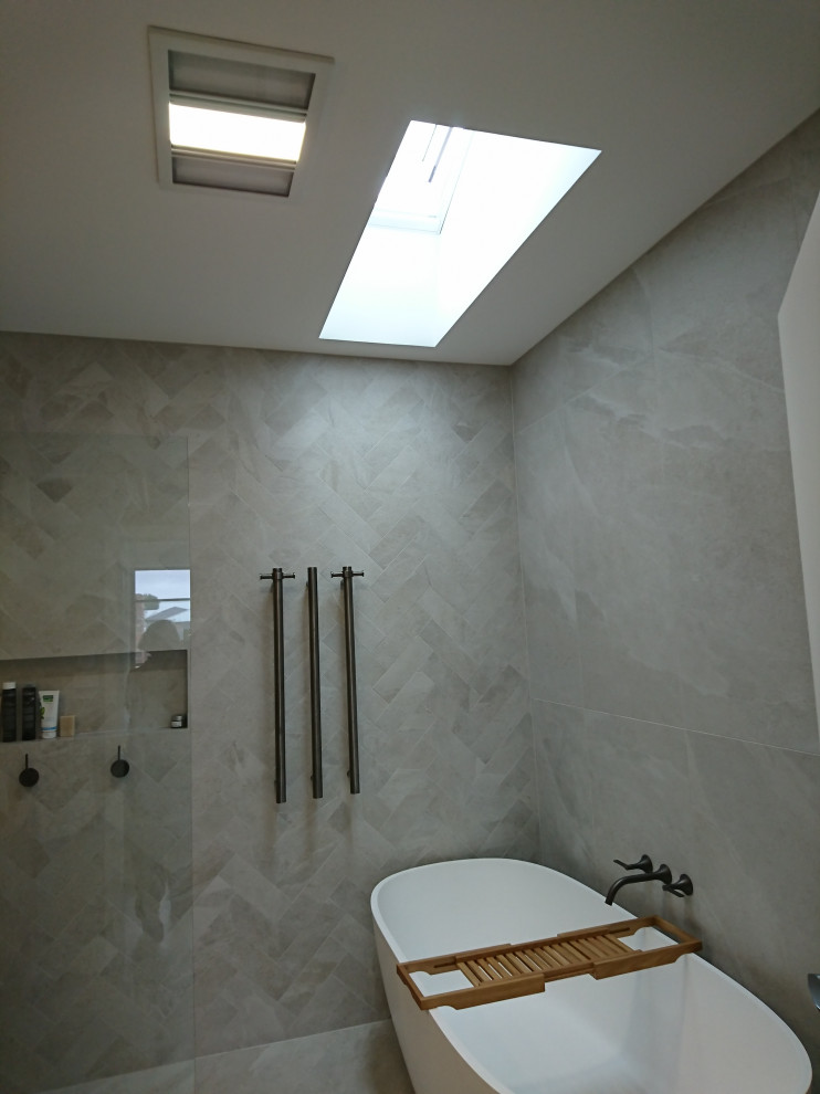 This is an example of a large modern wet room bathroom in Melbourne with flat-panel cabinets, medium wood cabinets, a freestanding tub, a one-piece toilet, gray tile, porcelain tile, beige walls, porcelain floors, a vessel sink, wood benchtops, grey floor, an open shower, a double vanity and a floating vanity.