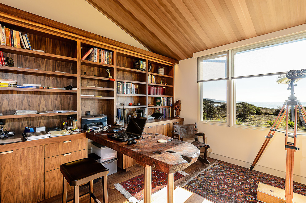 This is an example of a midcentury home office in San Francisco with beige walls, dark hardwood floors and a built-in desk.