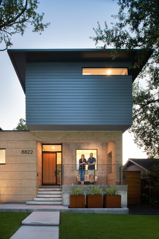 This is an example of a mid-sized midcentury two-storey blue house exterior in Houston with concrete fiberboard siding, a hip roof, a mixed roof, a brown roof and shingle siding.
