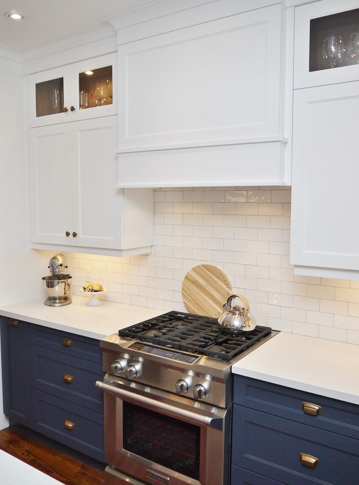 Mid-sized transitional l-shaped medium tone wood floor and brown floor eat-in kitchen photo in Toronto with an undermount sink, shaker cabinets, blue cabinets, quartz countertops, white backsplash, subway tile backsplash, stainless steel appliances, an island and white countertops