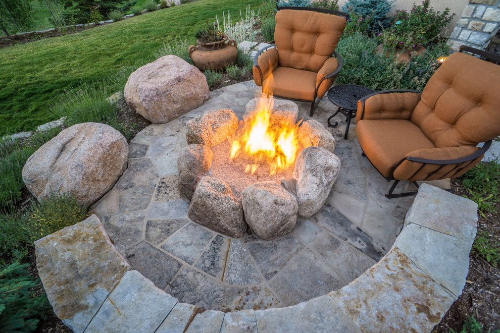 Large traditional backyard patio in Denver with a fire feature and natural stone pavers.
