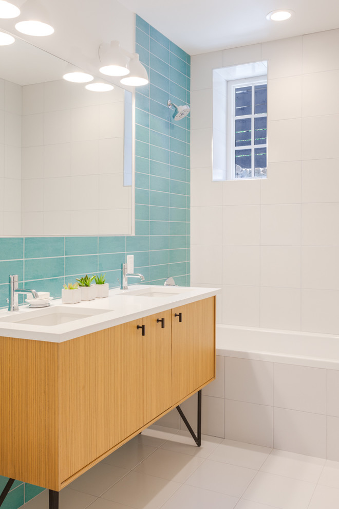 Photo of a small contemporary kids bathroom in Denver with flat-panel cabinets, light wood cabinets, a drop-in tub, a shower/bathtub combo, a one-piece toilet, blue tile, ceramic tile, white walls, ceramic floors, an undermount sink, engineered quartz benchtops, white floor and an open shower.
